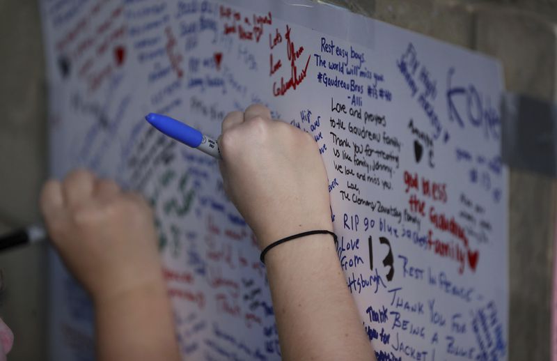 Fans write messages during a candlelight vigil to honor Columbus Blue Jackets hockey player Johnny Gaudreau, Thursday, Sept. 4, 2024, outside of Nationwide Arena in Columbus, Ohio. Gaudreau and his brother Matthew were killed by a motor vehicle last week while riding bicycles. (AP Photo/Joe Maiorana)