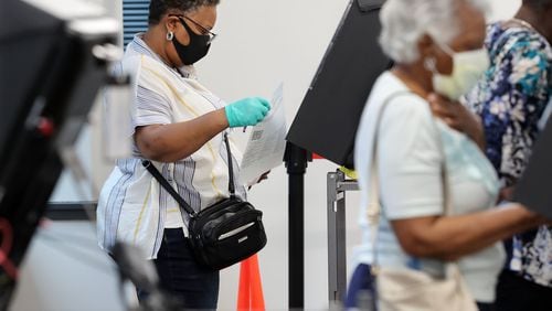A voter wears a mask and gloves to cast her vote at stations at least six feet apart on the first day of early voting at the Cobb County Board of Elections & Registration on Monday, May 18, 2020, in Marietta. CURTIS COMPTON / CCOMPTON@AJC.COM