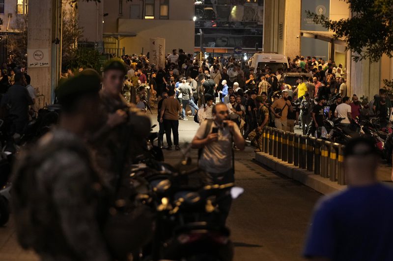 People gather outside the American University hospital after the arrival of several people who were wounded by exploding handheld pagers, in Beirut, Lebanon, Tuesday, Sept. 17, 2024. (AP Photo/Hassan Ammar)