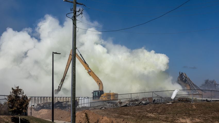 Excavators move debris at BioLab at mid-morning Wednesday, Oct 2, 2024 as a large mile-long plume was still visible over Conyers as crews worked at the plant that caught on fire days earlier. But as the sun lifted above the horizon, so did the shelter-in-place order for Rockdale County residents. Those living nearby have been advised to stay inside every evening through early morning until Friday. (John Spink/AJC)