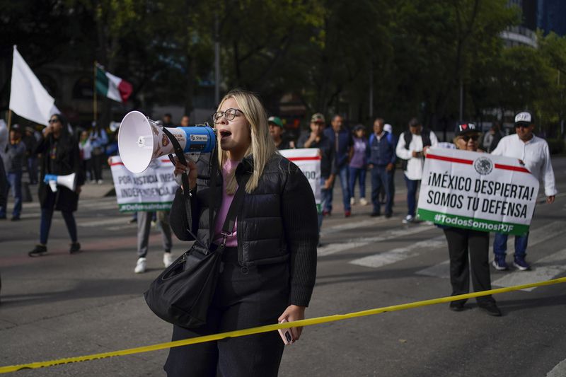 A demonstrator yells into a megaphone to protest against the judicial reform bill outside the Senate in Mexico City, Thursday, Sept. 5, 2024, the day after Congress passed legislation that would require all judges to stand for election. (AP Photo/Felix Marquez)