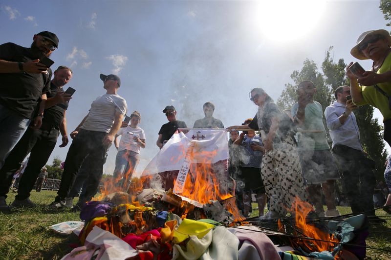 FILE - Opponents of gay rights burn LGBTQ+ flags and symbols as they try to interfere a pride event in Tbilisi, Georgia, on July 8, 2023. (AP Photo/Zurab Tsertsvadze, File)