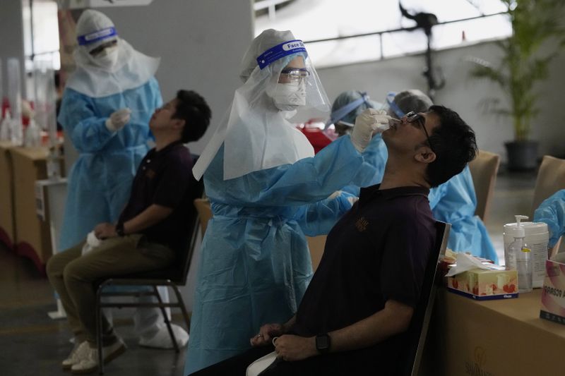 FILE - Shopping mall workers undergo a COVID-19 swab test during the opening at the Paragon shopping mall in Bangkok, Thailand, Wednesday, Sept. 1, 2021. (AP Photo/Sakchai Lalit, File)