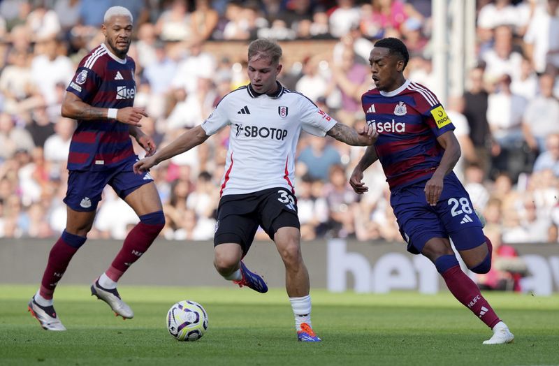 Fulham's Emile Smith Rowe and Newcastle United's Joe Willock, right, battle for the ball during the English Premier League soccer match between Fulham and Newcastle United at Craven Cottage, London, Saturday Sept. 21, 2024. (Jonathan Brady/PA via AP)