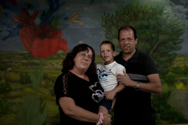 Ariel Heller, 4, poses for a portrait with his parents Anna, left, and Alex, right, as the family was invited for a special tour after he accidentally broke an ancient jar at the Reuben and Edith Hecht Museum in Haifa, Israel, Friday, Aug. 30, 2024. The boy who accidentally broke a rare 3,500-year-old jar in an Israeli museum has been forgiven and invited back, as curators hope to turn the disaster into a teachable moment. (AP Photo/Maya Alleruzzo)