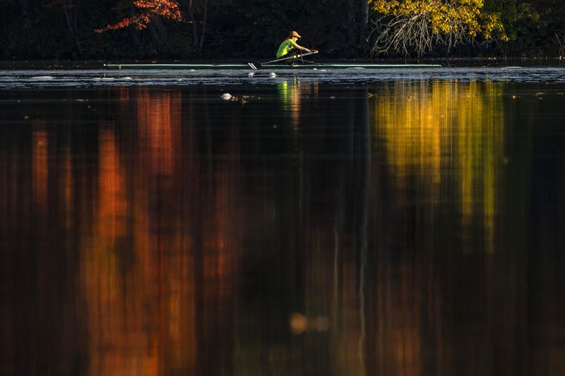 FILE - Fall foliage reflects on the Androscoggin River as Kathy Thorson rows a single scull, Oct. 12, 2021, in Brunswick, Maine. (AP Photo/Robert F. Bukaty, File)