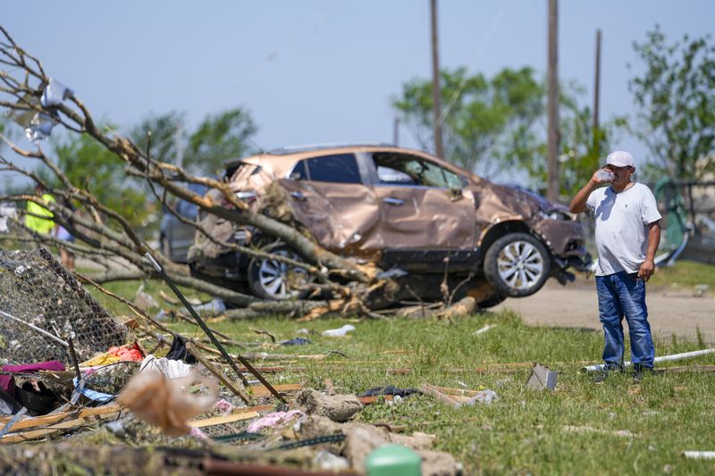 A man surveys damage to a neighbor's home after a deadly tornado rolled through, Sunday, May 26, 2024, in Valley View, Texas. Powerful storms left a wide trail of destruction Sunday across Texas, Oklahoma and Arkansas after obliterating homes and destroying a truck stop where drivers took shelter during the latest deadly weather to strike the central U.S. (AP Photo/Julio Cortez)