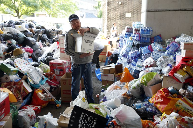 FILE - A man sorts articles of food, clothing and household items for those made homeless by the massive fire in Grenfell Tower, in London, Thursday, June 15, 2017. (AP Photo/Alastair Grant, File)