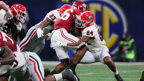 Georgia Bulldogs defensive back Malaki Starks (24) and Georgia linebacker C.J. Allen (33) tackle Alabama Crimson Tide running back Jam Miller (26) during the SEC Championship football game at the Mercedes-Benz Stadium in Atlanta, on Saturday, December 2, 2023. (Jason Getz / Jason.Getz@ajc.com)