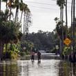 FILE - Men walk down a street flooded by Hurricane Helene in the Shore Acres neighborhood Sept. 27, 2024, in St. Petersburg, Fla. (AP Photo/Mike Carlson, File)