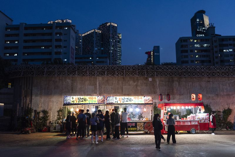 People form lines in front of food trucks at Yeouido Hangang Park, a popular destination for both residents and tourists, as dusk falls in Seoul, Wednesday, May 22, 2024. (AP Photo/Jae C. Hong)