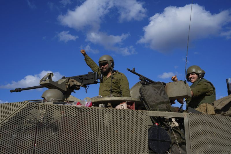 Israeli soldiers raise their fists from a moving APC in northern Israel near the Israel-Lebanon border, Tuesday, Oct. 1, 2024. (AP Photo/Baz Ratner)