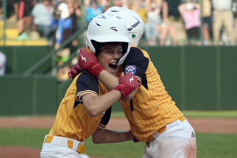 Lake Mary, Fla.'s Hunter Alexander, left, is hugged by Chase Anderson, right, after Alexander's bunt single allowed the winning run to score from second base Taiwan to win the game during the eighth inning of the the Little League World Series Championship game in South Williamsport, Pa., Sunday, Aug. 25, 2024. (AP Photo/Tom E. Puskar)