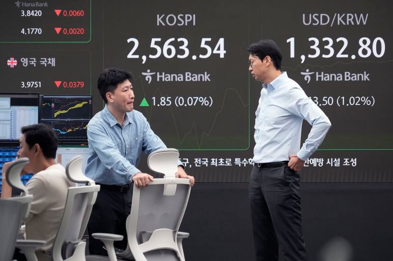 Currency traders work near a screen showing the Korea Composite Stock Price Index (KOSPI) and the foreign exchange rate between U.S. dollar and South Korean won, right, at the foreign exchange dealing room of the KEB Hana Bank headquarters in Seoul, South Korea, Friday, Oct. 4, 2024. (AP Photo/Ahn Young-joon)