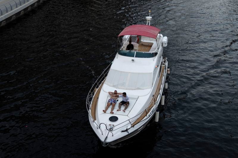 People sit on a boat as it sails along Dubai Marina, United Arab Emirates, Tuesday, Aug. 13, 2024. (AP Photo/Altaf Qadri)