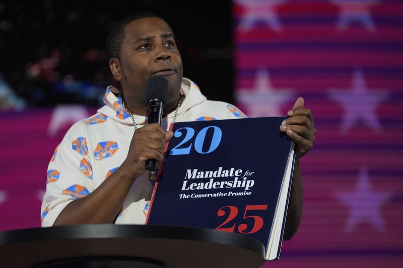 Kenan Thompson holds a copy of Project 2025 during the Democratic National Convention Wednesday, Aug. 21, 2024, in Chicago. (AP Photo/Paul Sancya)