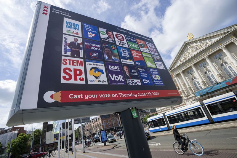Een fietser passeert een reclamebord voor de Europese verkiezingen voor het Concertgebouw in Amsterdam, Nederland, woensdag 5 juni 2024.  Kiezers in de Europese Unie zullen vanaf donderdag 6 juni wetgevers voor de Grondwetgevende Vergadering kiezen.  (AP-foto/Peter DeJong)