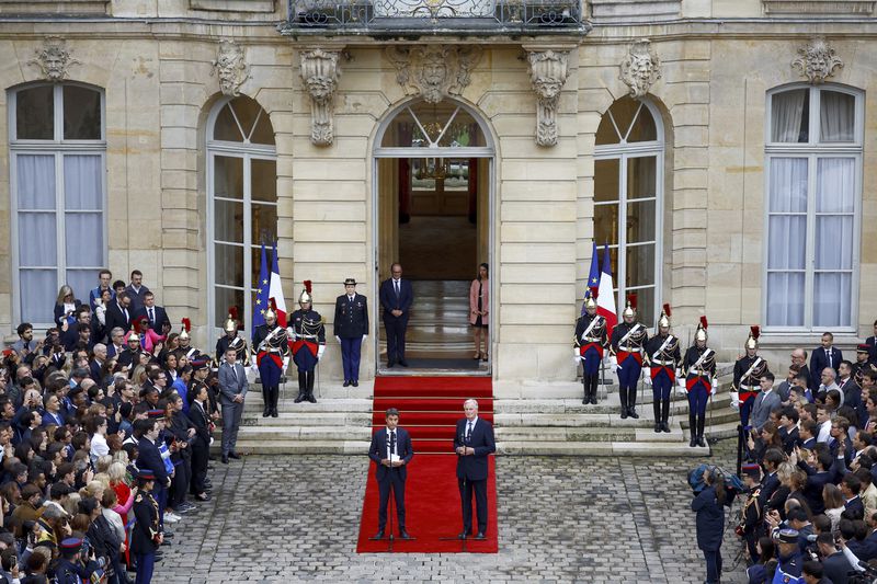 Outgoing French Prime Minister Gabriel Attal, center left, and new French prime minister Michel Barnier speak during the handover ceremony, Thursday, Sept. 5, 2024 in Paris. President Emmanuel Macron has named EU's Brexit negotiator Michel Barnier as France's new prime minister after more than 50 days of caretaker government. (Sarah Meyssonnier/Pool Photo via AP)