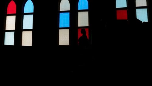 A woman is silhouetted against the stained-glass windows at the Ryman Auditorium, known as the Mother Church of Country music, in Nashville, Tenn., on July 30, 2024. (AP Photo/Luis Andres Henao)