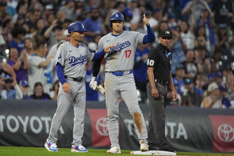 Los Angeles Dodgers third base coach Dino Ebel, left, congratulates Shohei Ohtani after he stole second base and advanced to third base on a throwing error by Colorado Rockies catcher Jacob Stallings in the second inning of a baseball game, Friday, Sept. 27, 2024, in Denver. (AP Photo/David Zalubowski)