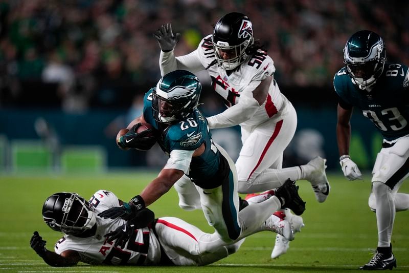 Philadelphia Eagles running back Saquon Barkley (26) falls with the ball near Atlanta Falcons cornerback Clark Phillips III, bottom, and Atlanta Falcons defensive end James Smith-Williams during the second half of an NFL football game Monday, Sept. 16, 2024, in Philadelphia. (AP Photo/Matt Slocum)