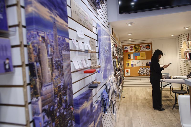 Beatrice Chen, executive director of Immigrant Social Services, checks her phone inside the Storefront for Ideas, Thursday, Aug. 8, 2024, in New York. (AP Photo/Kena Betancur)