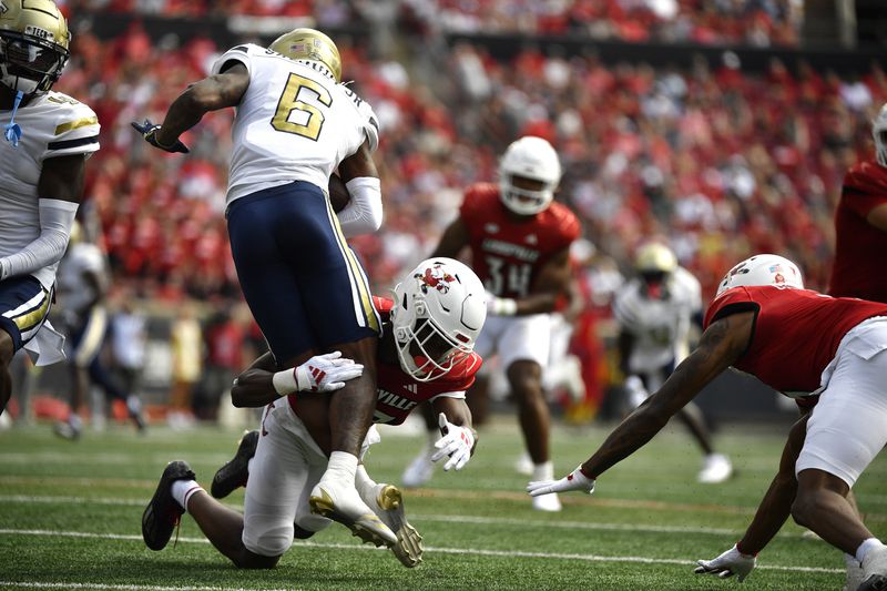 Louisville defensive back Tahveon Nicholson (23) grabs Georgia Tech running back Anthony Carrie (6) by the legs during the first half of an NCAA college football game in Louisville, Ky., Saturday, Sept. 21, 2024. (AP Photo/Timothy D. Easley)