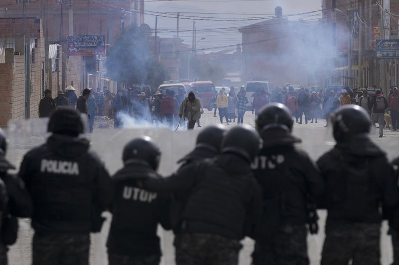 Police stand in front of supporters of former President Evo Morales, who are marching to La Paz to protest current President Luis Arce's government, in El Alto, Bolivia, Sunday, Sept. 22, 2024. (AP Photo/Juan Karita)