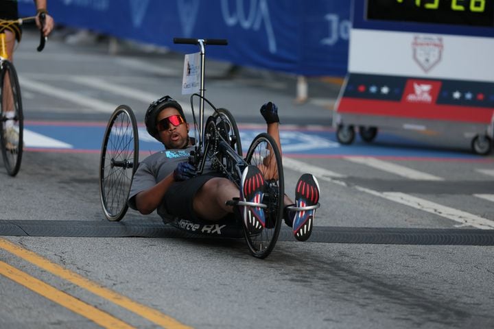 Cecil Williams crosses the finish line to win the handcycle division of the 55th running of the Atlanta Journal-Constitution Peachtree Road Race in Atlanta on Thursday, July 4, 2024.   (Jason Getz / AJC)