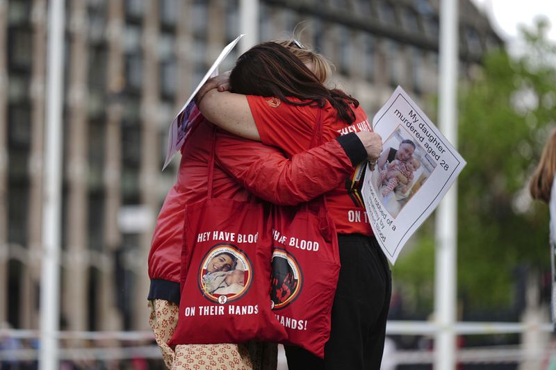Infected blood campaigners hug during a gathering at Parliament Square, ahead of the publication of the final report into the scandal, in London, Sunday, May 19, 2024. The final report of the U.K.’s infected blood inquiry will be published Monday, six years after it started its work. The inquiry heard evidence as to how thousands of people contracted HIV or hepatitis from transfusions of tainted blood and blood products in the 1970s and 1980s. (Aaron Chown/PA via AP)