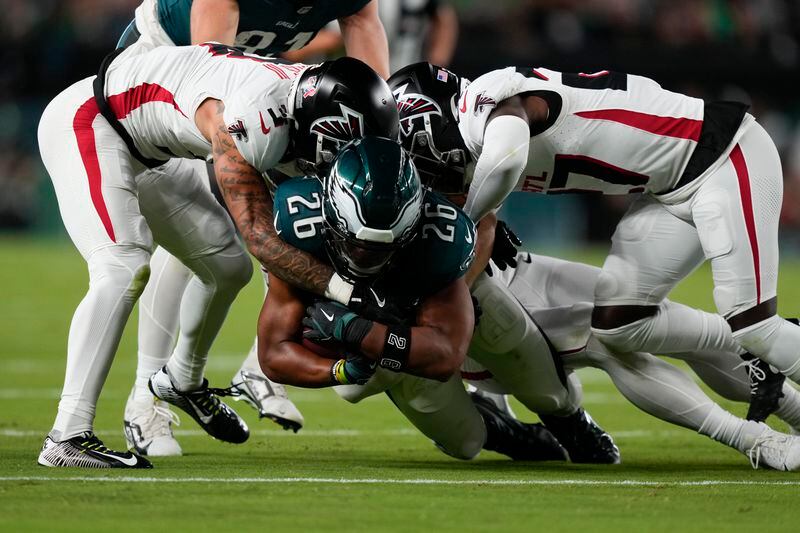 Philadelphia Eagles running back Saquon Barkley (26) is brought down during the first half of an NFL football game by Atlanta Falcons' Jessie Bates III, left, on Monday, Sept. 16, 2024, in Philadelphia. (AP Photo/Matt Slocum)