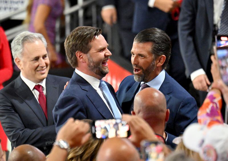 U.S. Sen. JD Vance (center), R-Ohio, and Donald Trump Jr. (right) share a smile as they wait for former President Donald Trump during the Republican National Convention in Milwaukee.