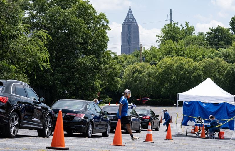 Workers at a CORE testing site at Antioch Baptist Church North in Northwest Atlanta collect covid-19 tests from a line of cars that disappears and wraps around the block Thursday afternoon July 16, 2020. Ben Gray for the Atlanta Journal-Constitution