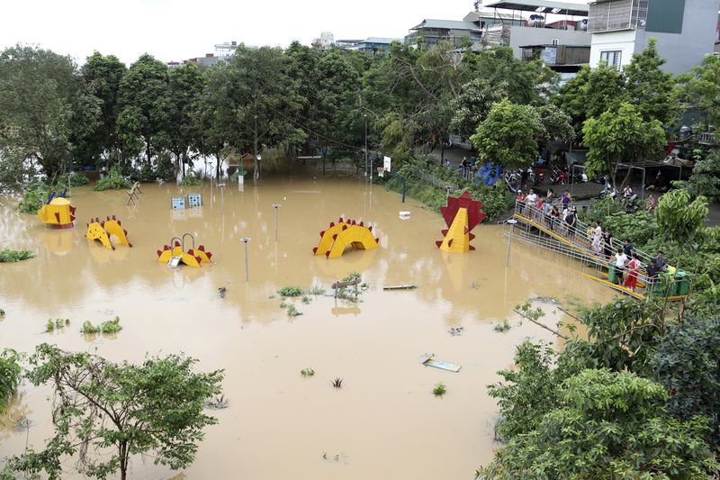 People watch a submerged dragon structure in a playground, following Typhoon Yagi in Hanoi, Vietnam on Tuesday, Sept. 10, 2024. (AP Photo/Huy Han)