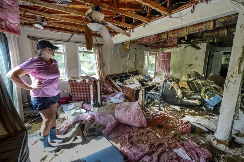 Cindy White looks over the devastation inside her home caused by Hurricane Helene, Tuesday, Oct. 1, 2024 in Morganton, N.C. The adjacent Catawba River flooded due to the torrential rains destroying the seven of family's nine homes on the property. (AP Photo/Kathy Kmonicek)