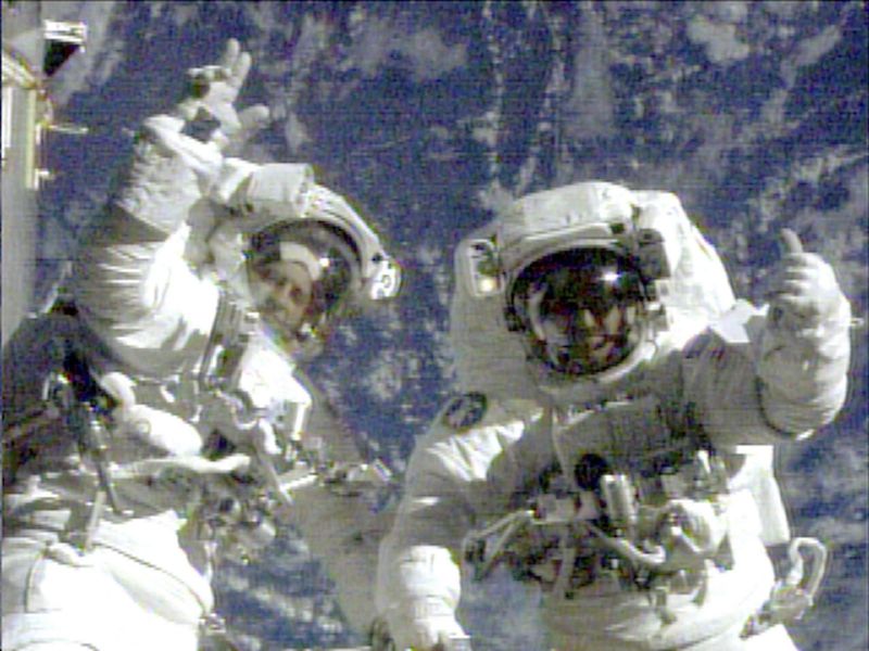 FILE - In this image from video provided by NASA, astronauts Richard Linnehan, left, and John Grunsfeld wave to the camera during their last few moments of the final spacewalk for the Hubble Space Telescope repair mission on March 8, 2002. (NASA via AP, File)