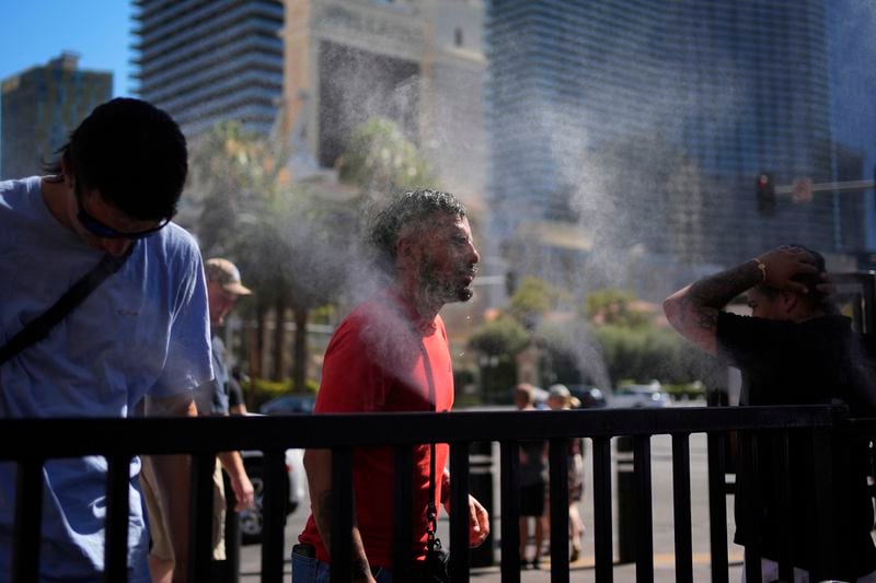People cool off in misters along the Las Vegas Strip, Sunday, July 7, 2024, in Las Vegas. A heat wave is spreading across the Western U.S., the National Weather Service said, sending many residents in search of a cool haven from the dangerously high temperatures. (AP Photo/John Locher)