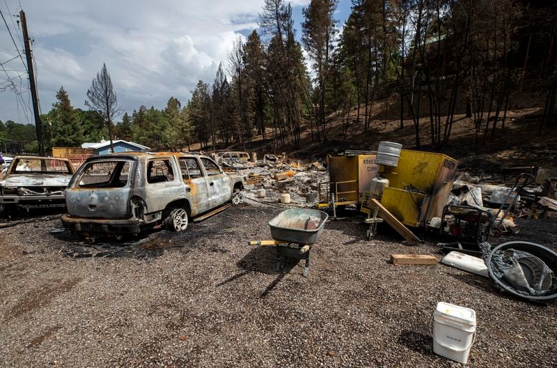 Charred cars sit around a flattened home that was destroyed by the South Fork Fire in the mountain village of Ruidoso, N.M., Saturday, June 22, 2024. Recent rains and cooler weather are helping more than 1,000 firefighters gain ground on two wildfires in southern New Mexico that have killed two people, destroyed hundreds of homes and forced thousands to flee. (AP Photo/Andres Leighton)