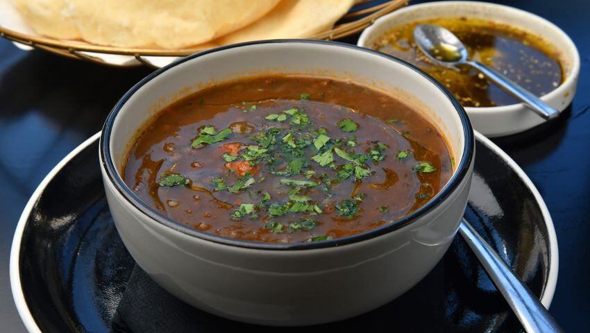 Fresh lentil soup in a white bowl, served in a restaurant setting