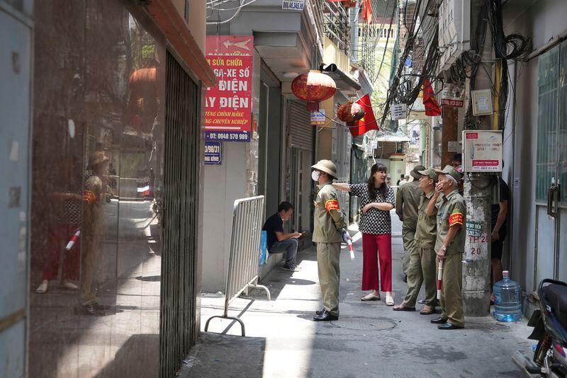 Security officers guard at the cordoned off entrance to the site of a fire in Hanoi, Vietnam Friday, May 24, 2024. State media said the overnight fire in a small apartment building has killed a number of people and injured several others. (AP Photo/Hau Dinh)