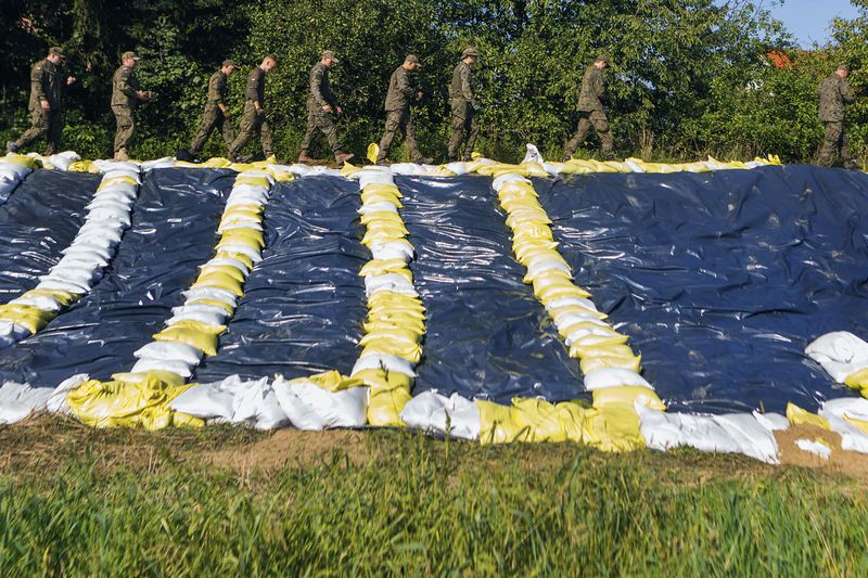 Soldiers who help strengthen the embankments and to prevent floodings walk by sandbags near the city of Wroclaw, southwestern Poland, Tuesday, Sept. 17, 2024. (AP Photo/Krzysztof Zatycki)