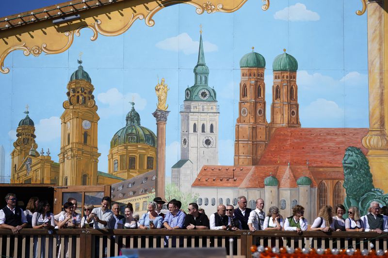 Visitors await the start of the 189th 'Oktoberfest' beer festival in front of paintings showing Munich landmarks in Munich, Germany, Saturday, Sept. 21, 2024. (AP Photo/Matthias Schrader)