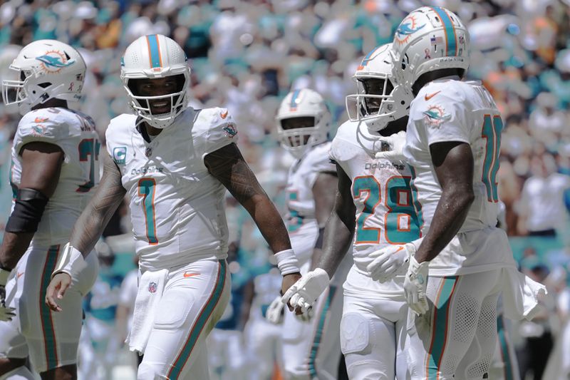 Miami Dolphins quarterback Tua Tagovailoa (1) celebrates a touchdown by running back De'Von Achane (28) during the first half of an NFL football game against the Jacksonville Jaguars, Sunday, Sept. 8, 2024, in Miami Gardens, Fla. (AP Photo/Rebecca Blackwell)