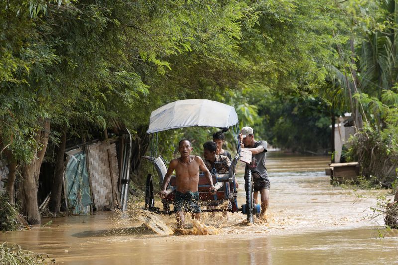 Local residents carrying food on their cart wade through a flooded road in Naypyitaw, Myanmar, Saturday, Sept. 14, 2024. (AP Photo/Aung Shine Oo)