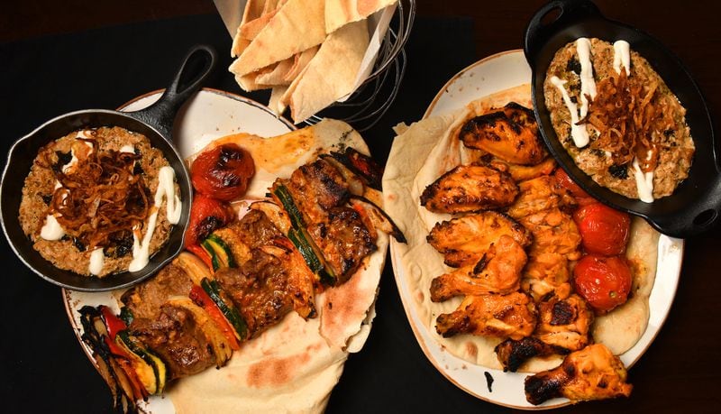 Kashk Bademjoon (eggplant spread with crispy mint and fried onions), Beef Shish Kebabs, Zafron Wings, and a second dish of Kashk Bademjoon. Shown with bread in a basket at top. (Styling by Peter Teimori / Chris Hunt for the AJC) 