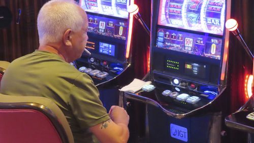 A gambler smokes while playing a slot machine at the Hard Rock casino in Atlantic City, N.J., on Aug. 8, 2022. (AP Photo/Wayne Parry)