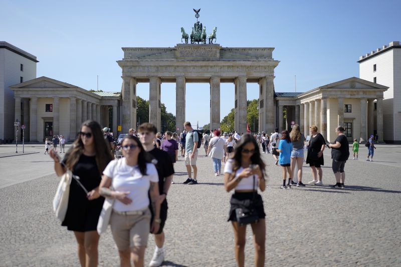 People stand in front of Berlin's famous landmark 'Brandenburg Gate' in Berlin, Germany, Monday, Sept. 2, 2024. (AP Photo/Markus Schreiber)