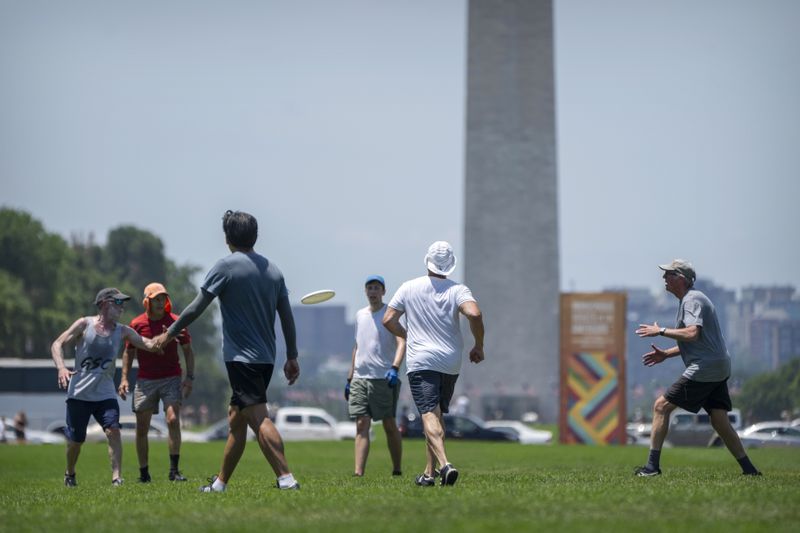 People play ultimate Frisbee on the National Mall in Washington, Wednesday, June 19, 2024. High temperatures are expected to stay in the 90s in the nation's capital for the rest of the week as a heat wave builds into the Northeast. (AP Photo/Mark Schiefelbein)