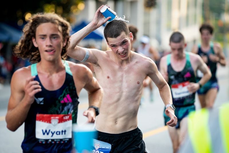 A runner dumps water on his head during the 55th running of the Atlanta Journal-Constitution Peachtree Road Race at "Cardiac Hill" on Peachtree Road NW in Atlanta on Thursday, July 4, 2024. (Seeger Gray / AJC)