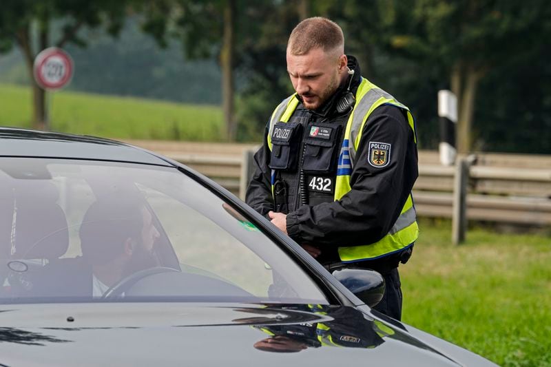 A German police officer checks the details of a French car near the border to Belgium in Aachen, Germany, Monday, Sept. 16, 2024, as Germany begins carrying out checks at all its land borders. (AP Photo/Martin Meissner)